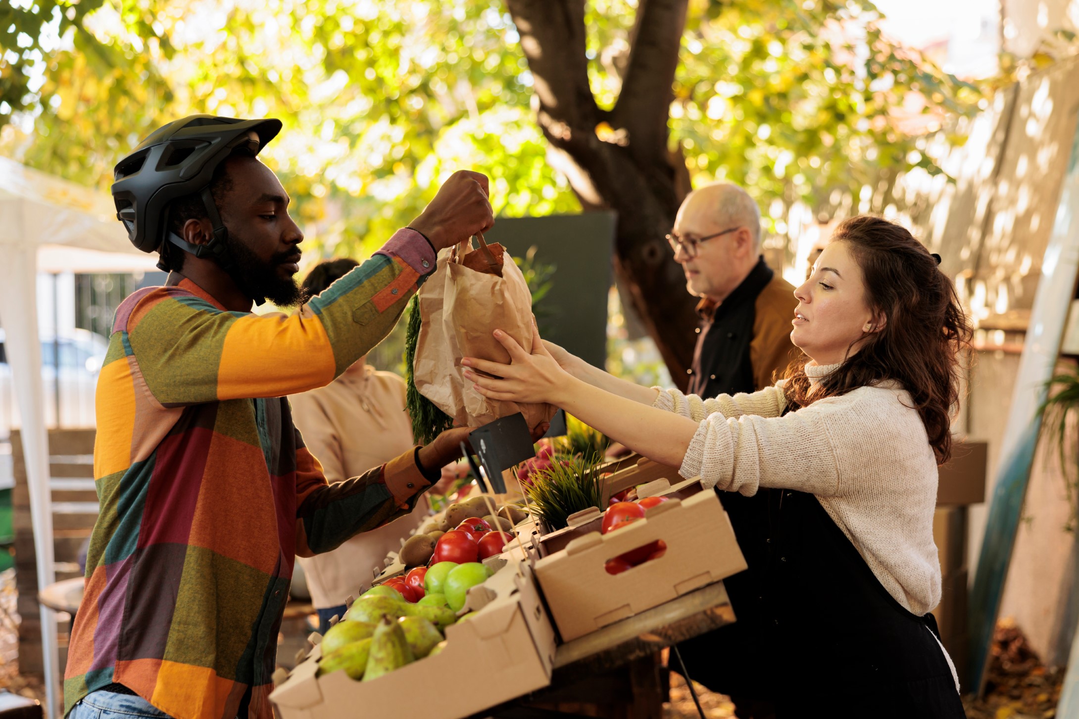 Female small business owner giving order of fresh produce to african american courier, helping with fruits and vegetables delivery. Woman farmer preparing organic eco products.